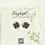 Red and green floral oxidized silver stud earrings with mirror accents by Nazāqat, on decorative backing card