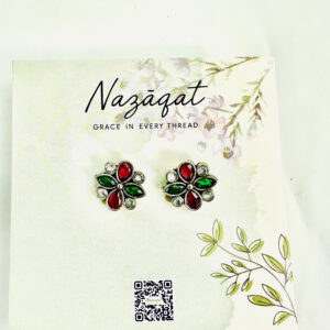Red and green floral oxidized silver stud earrings with mirror accents by Nazāqat, on decorative backing card