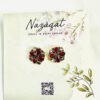 Floral oxidized silver stud earrings with red stones by Nazāqat, displayed on a soft floral backing card