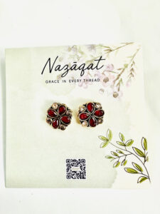 Floral oxidized silver stud earrings with red stones by Nazāqat, displayed on a soft floral backing card