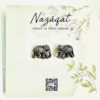 Oxidized silver elephant motif stud earrings by Nazāqat, displayed on floral backing card