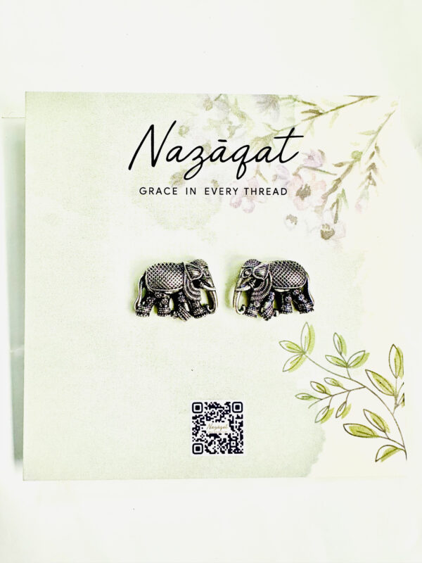 Oxidized silver elephant motif stud earrings by Nazāqat, displayed on floral backing card