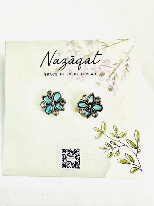 Oxidized silver floral earrings with blue petal-shaped stones and mirror accents by Nazāqat, displayed on a floral card