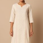 "Elegant ivory cotton kurta with subtle thread embroidery and notch neckline, modeled on a beige background – Nazāqat ethnic wear"