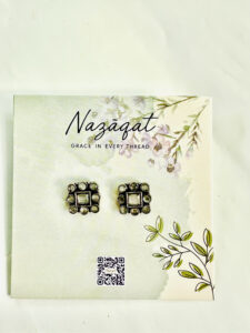 Square oxidized silver stud earrings with central and circular mirror design by Nazāqat, displayed on floral backing